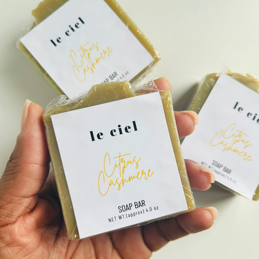 Hand holding a soap bar labeled 'le ciel' with another soap bar in the background.